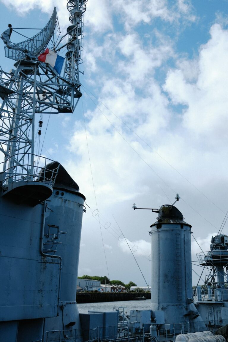 A naval ship's antenna providing a striking view against a bright blue sky, showing advanced communication equipment.