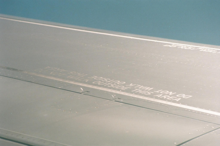 Close-up of an airplane wing with visible safety warnings and text.